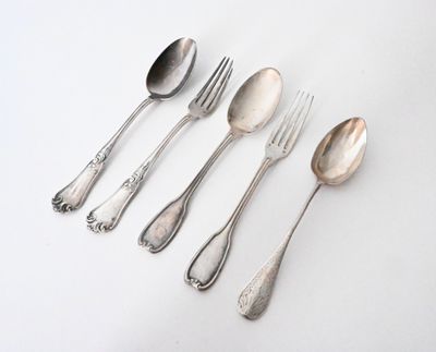 five silver spoons and two silver spoons on a white surface