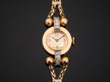 a close up of a gold watch with a chain around it