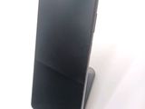 a black cell phone sitting on a stand on a white surface