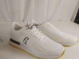 men ' s white sneakers with black numbers and yellow soles on a white surface