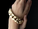 a woman ' s hand with a gold bracelet on her wrist