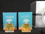 two bottles of perfume sitting on top of a table next to a clock