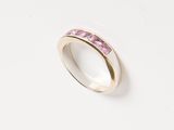 a close up of a ring with pink stones on a white surface