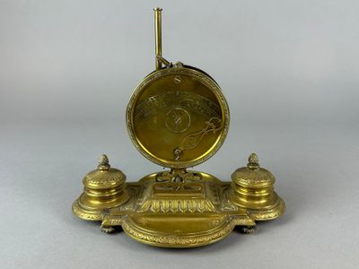 une horloge dorée posée sur un socle, sur une surface blanche