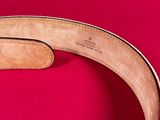 a close up of a brown belt on a pink surface