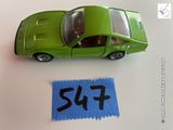 une petite voiture verte posée à côté d'une feuille de papier bleue