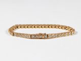 a gold bracelet with diamonds on a white background