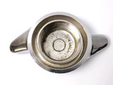 a silver tea pot with a handle on a white surface