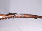 un vieux fusil en bois coiffé d'un chapeau vert sur fond blanc