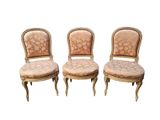 On voit trois chaises anciennes aux assises rembourrées, mises en valeur sur un fond blanc