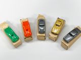 cinq petites voitures miniatures alignées les unes à côté des autres sur une boîte en carton