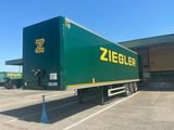 a green semi trailer parked in a parking lot
