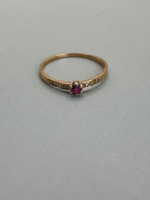 a close up of a gold ring with a red stone