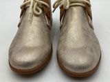 the children ' s shoes are gold and brown with laces on them