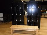 several black lockers and a bench in a room with wood floors