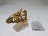 une bague en or ornée d'une feuille, à côté d'une étiquette de prix