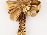 une image représentant une broche en or ornée de fleurs