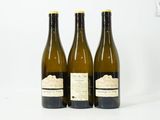 trois bouteilles de vin posées les unes à côté des autres sur une surface blanche