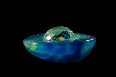 un bol en verre contenant une bille, sur fond noir