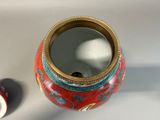 a red and gold vase with a mirror on it