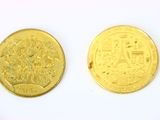 deux pièces d'or posées l'une à côté de l'autre sur une surface blanche
