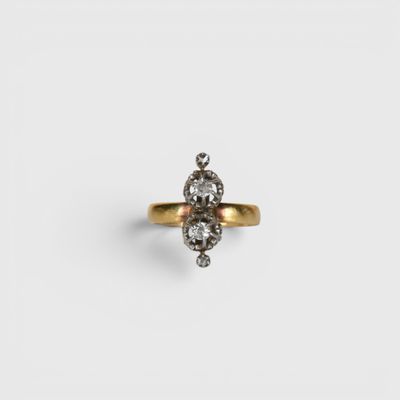 a close up of a gold ring with two diamonds on it