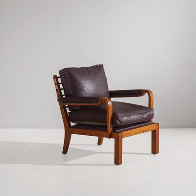 un fauteuil en cuir marron foncé avec une structure en bois et des accoudoirs