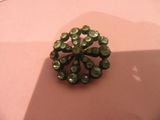 a green brooch on top of a pink surface