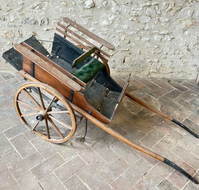 a small wooden cart with a green bag in it
