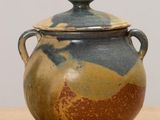 a brown and blue vase with a lid on a table