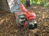 une tondeuse à gazon rouge qui est posée au milieu des feuilles