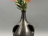 un vase noir contenant des fleurs orange, posé sur une table