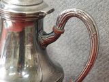 une théière en argent posée sur une table rouge