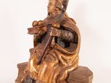 bronze statue of a man sitting on a bench with a violin