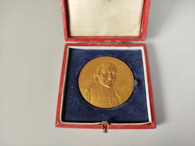 l'image d'une médaille d'or dans un coffret rouge posé sur un fond blanc
