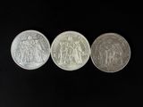 three silver coins, one of which is a sovereign and one of which is a sovereign