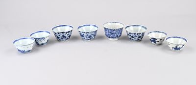 plusieurs tasses et soucoupes bleues et blanches posées sur une surface blanche