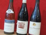 trois bouteilles de vin sont alignées sur une table en bois