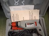 a corded drill in a plastic box with a paper