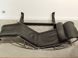 a black leather chaise lounger in the corner of a room