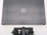 dell laptop with power cord and charger sitting on a white surface