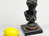 a small statue of a boy with a lemon next to it