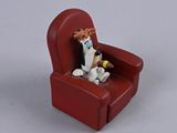 toy figurine of a dog sitting in a red chair with a bottle of wine