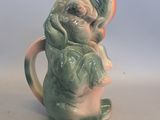 a small ceramic elephant holding a banana in its trunk