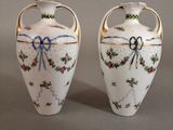 two white vases with flowers on them on a table