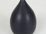 a black vase that is sitting on a white surface