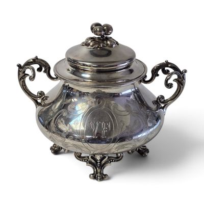 une théière en argent avec un couvercle, posée sur un socle