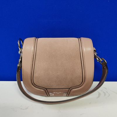 a pink leather cross body bag on a white table