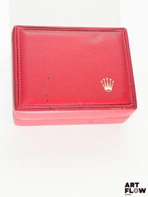une boîte rouge ornée d'une couronne, posée sur un fond blanc