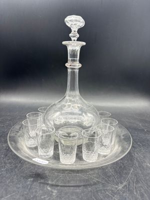 une photo représentant une carafe en verre et six verres à shot posés sur un plateau